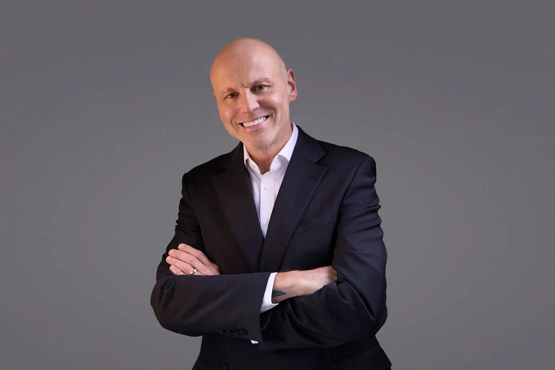 Brad Burton in a tailored suit, arms folded, smiling