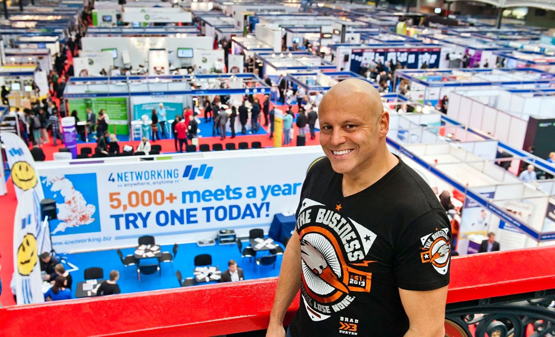 Brad overlooking a huge exhibition hall from a balcony above the 4Networking stand, with the '5,000+ meets a year' branding visible below