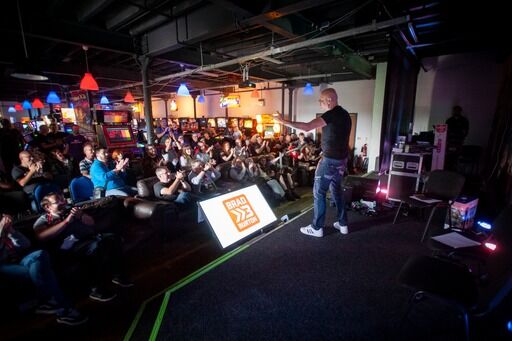 Brad performing in the round to an intimate, packed crowd at an arcade bar venue under neon lighting