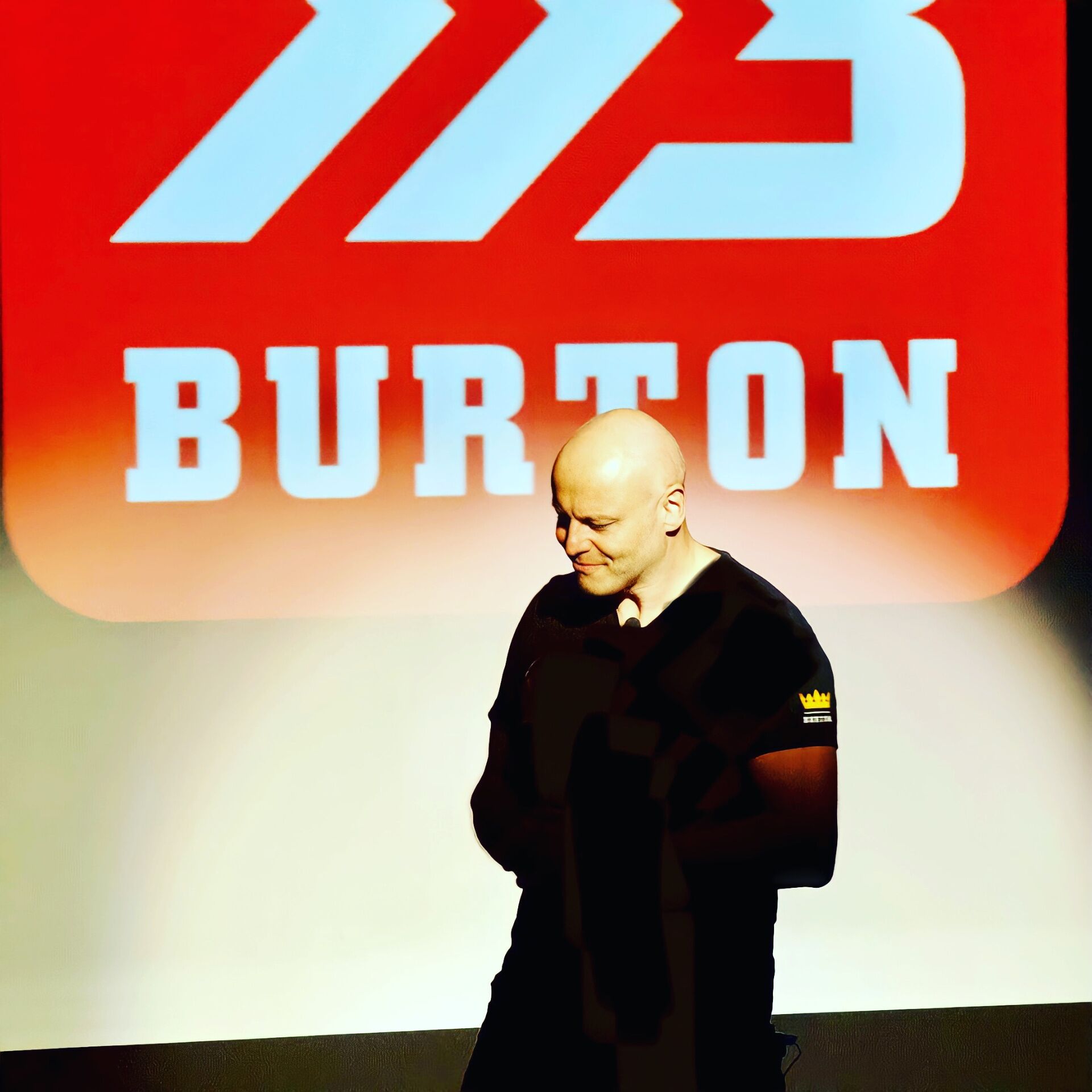 Brad mid-keynote in front of a giant BB Burton logo backdrop