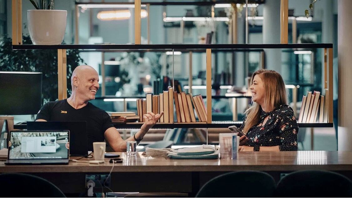 Brad mid-laugh in a relaxed podcast / long-form interview at a shared workspace